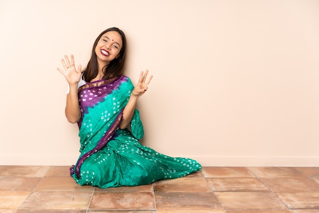 Jonge Indische vrouwenzitting op de vloer die acht met vingers telt