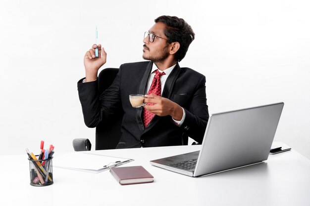 Jonge indische zakenman die aan laptop werkt en thee drinkt op kantoor.