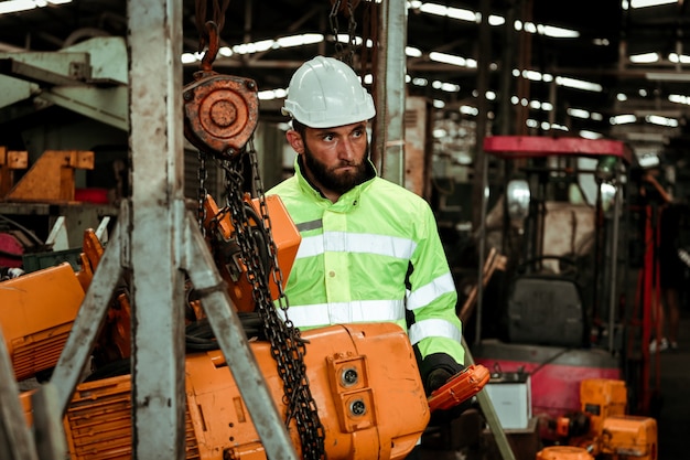 Jonge industriële werknemer man aan het werk met metalen machine in fabriek met veel apparatuur