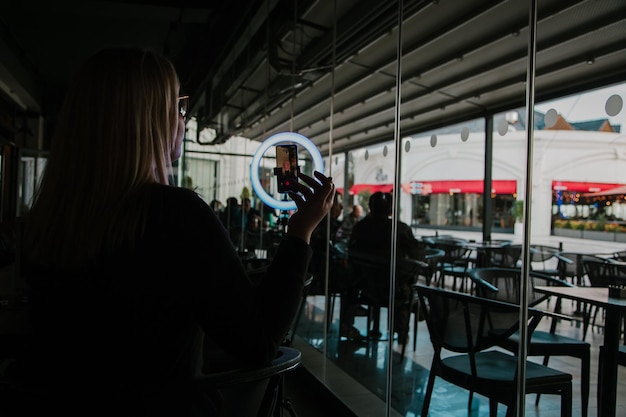 Jonge influencer voor de camera en selfie-ringlicht leest een tekst SMM-manager