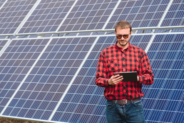 Jonge ingenieur met tabletcomputer die zich in openlucht dichtbij zonnepanelen bevindt