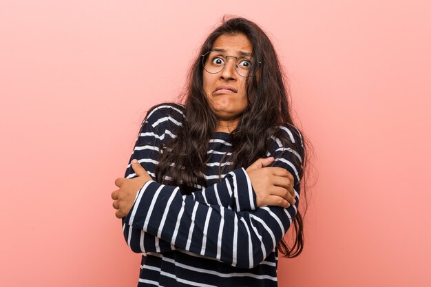 Jonge intellectuele Indiase vrouw die koud wordt door een lage temperatuur of een ziekte.