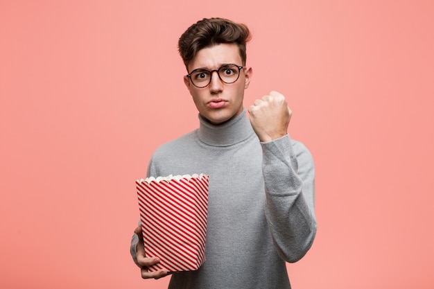 Jonge intellectuele mens die een popcornemmer houdt die nummer één met vinger toont.