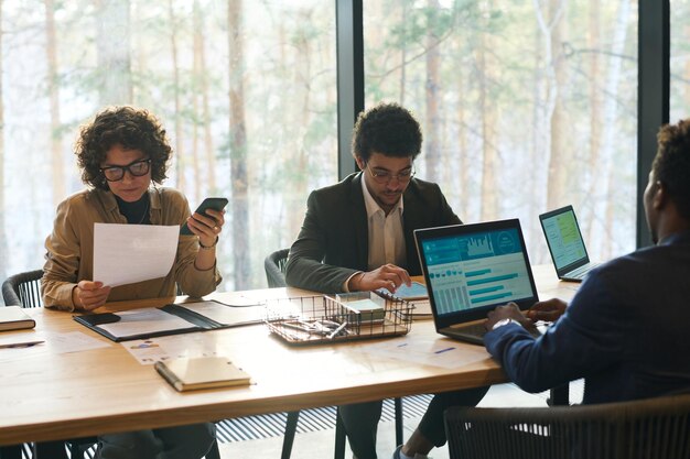 Jonge interculturele collega's zitten aan tafel in directiekamer en werken