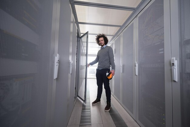 jonge IT-technicus met behulp van een digitale kabelanalysator op een server in een groot datacentrum