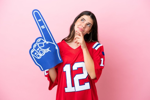 Jonge Italiaanse fan vrouw met schuim hand geïsoleerd op roze achtergrond en opzoeken