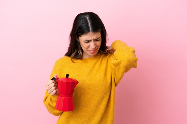 Jonge italiaanse vrouw met een koffiezetapparaat geïsoleerd op een roze achtergrond die lijdt aan pijn in de schouder omdat ze moeite heeft gedaan