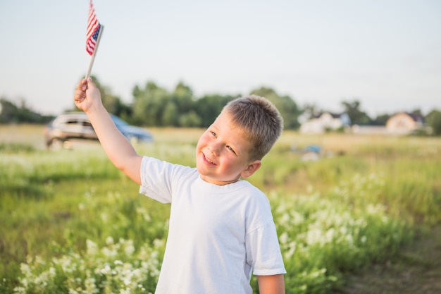 Jonge jongen 4 jaar oud met een Amerikaanse vlag bij zonsondergang in veld