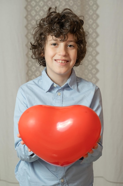 Jonge jongen die een ballon in de vorm van een hart geeft. Kinderen geven liefde concept.