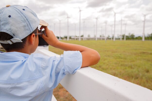 Jonge jongen die foto van windturbine in veld neemt