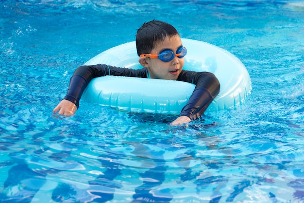 Jonge jongen die in pool zwemt.