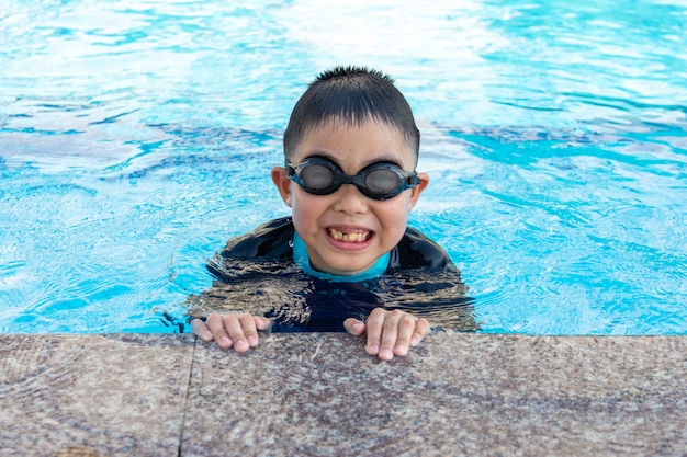 Jonge jongen die in pool zwemt.