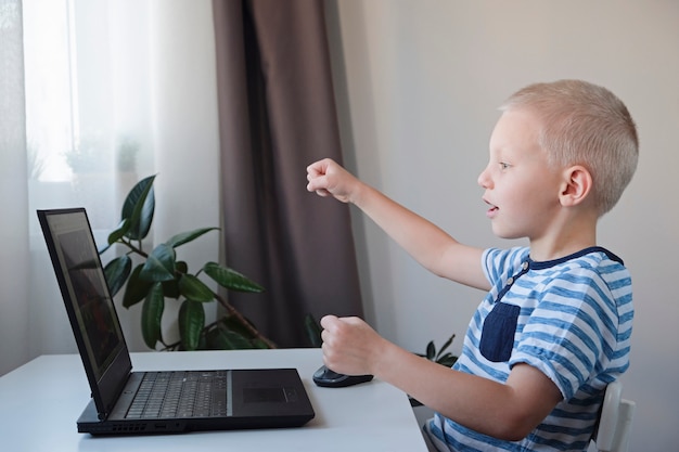 Jonge jongen die of op een computer thuis werkt speelt. E-lessen voor kinderen.