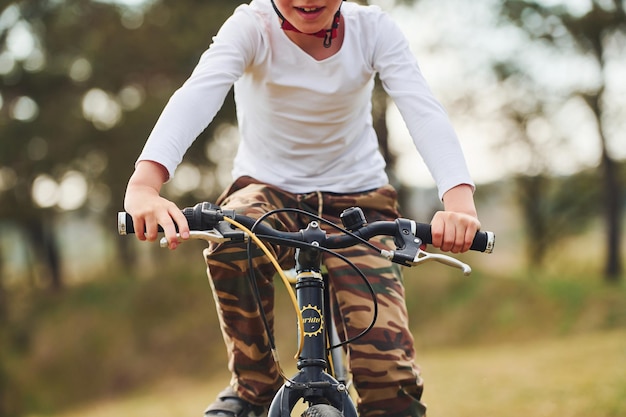 Jonge jongen die overdag buiten in het bos fietst