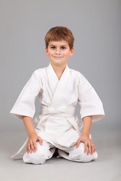 Jonge jongen die witte karatekimono draagt