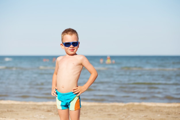 Jonge jongen die zonnebril op het strand draagt