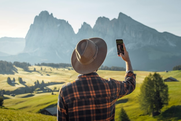 jonge jongen in hoed en geruite hemd die een selfie neemt in Alpe di Siusi Dolomieten