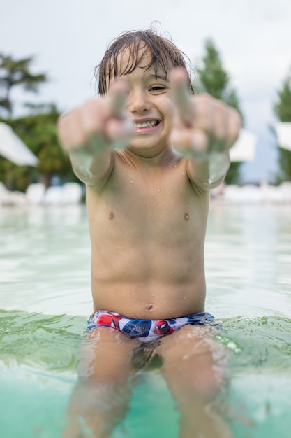 Jonge jongen kind kind spetteren in zwembad plezier vrijetijdsbesteding