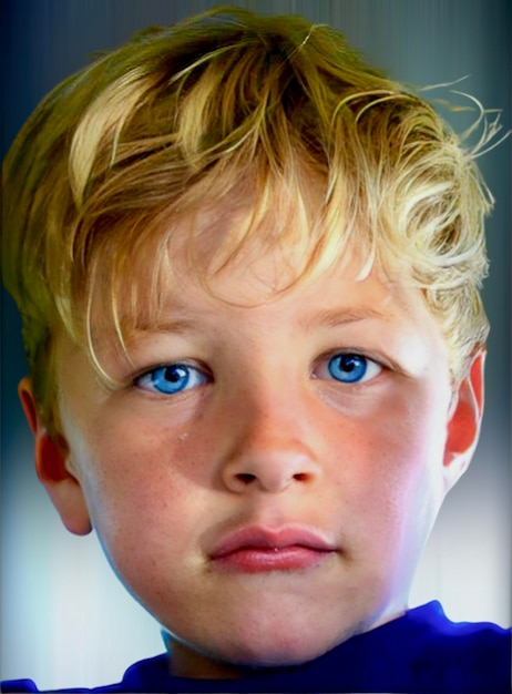 Foto jonge jongen met blauwe ogen en blond haar staart door de lens van de camera.