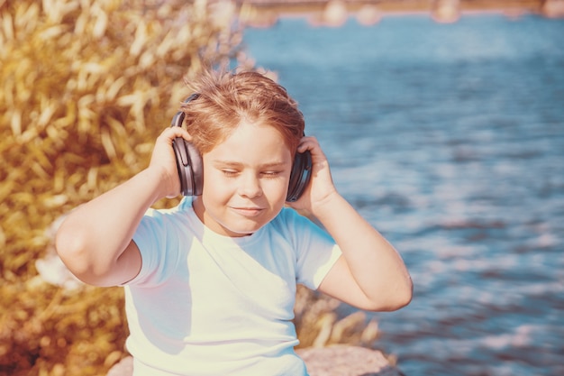 Jonge jongen met koptelefoon luisteren naar muziek buitenshuis