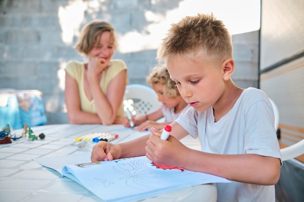 Jonge jongen tekenen op kamperen in de zomer met haar familie