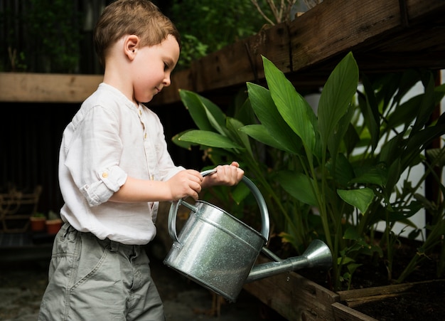 Jonge jongen water planten in de tuin