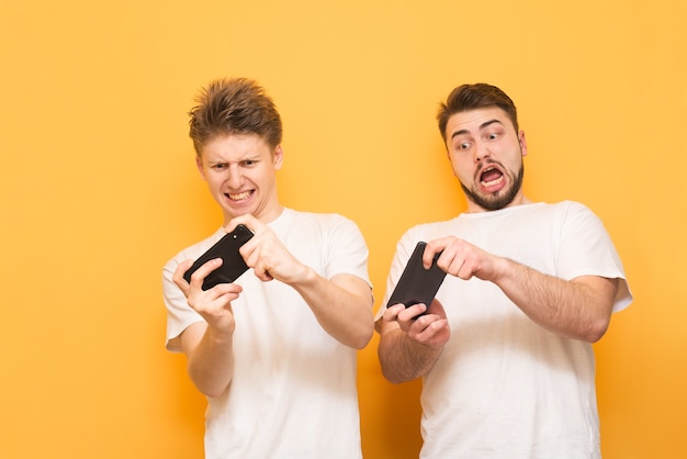 jonge jongens op geel dragen een wit T-shirt en spelen spelletjes op hun smartphone