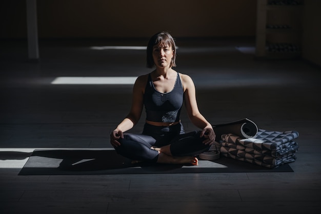 Jonge kalme yogivrouw in gemakkelijke yoga stelt. yoga studio interieur.