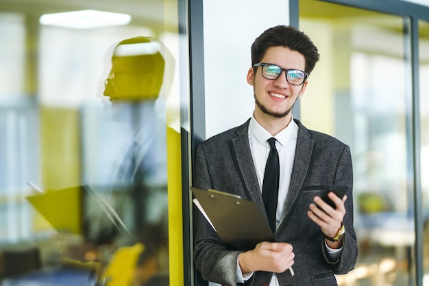 Jonge kantoormedewerker in glazen met behulp van mobiele slimme telefoon. Zakenman houdt telefoon in de hand.