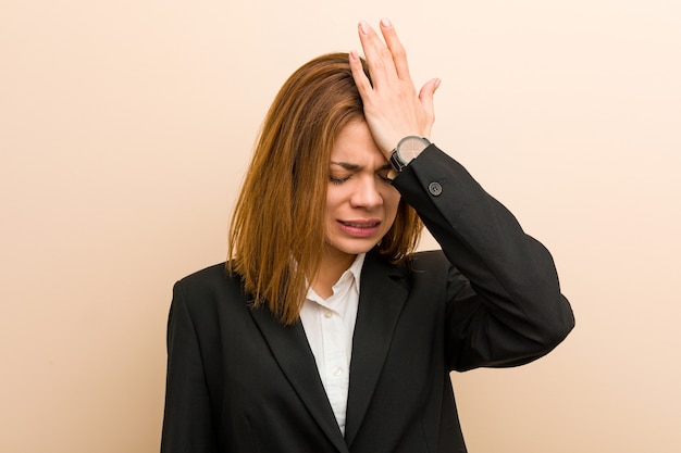 Jonge kaukasische bedrijfsvrouw die iets vergeten, voorhoofd met handpalm slaan en ogen sluiten.