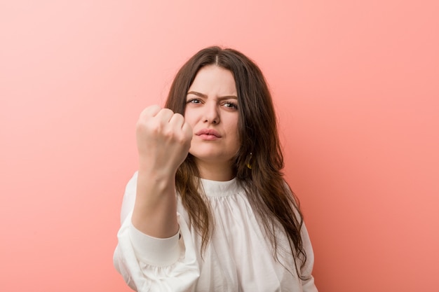 Jonge Kaukasische curvy vrouw die zich tegen roze bevindt