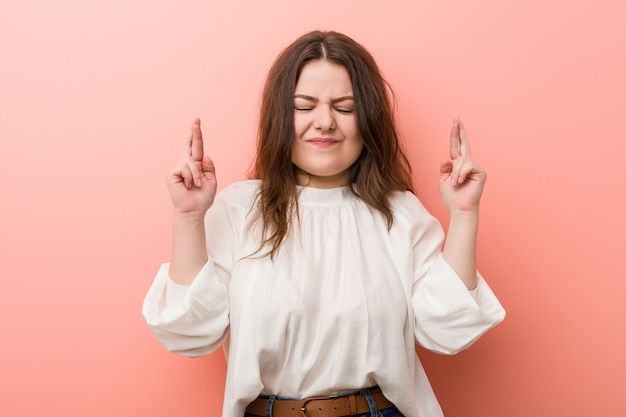 Jonge Kaukasische curvy vrouw die zich tegen roze muur bevindt