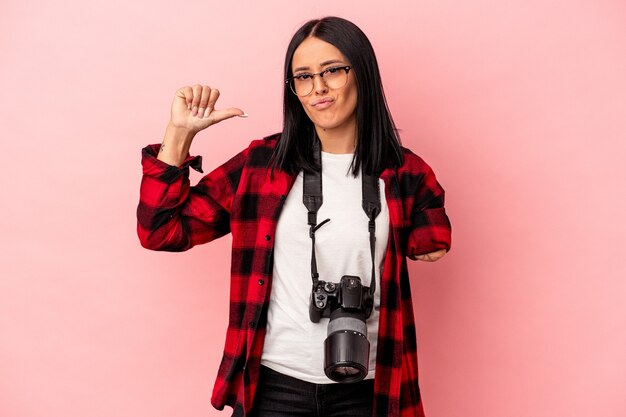 Jonge kaukasische fotografievrouw met één arm geïsoleerd op roze achtergrond voelt zich trots en zelfverzekerd, voorbeeld om te volgen.