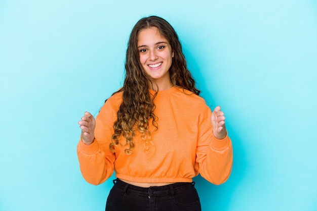 Jonge kaukasische krullende haarvrouw die iets met beide handen, productpresentatie houdt.