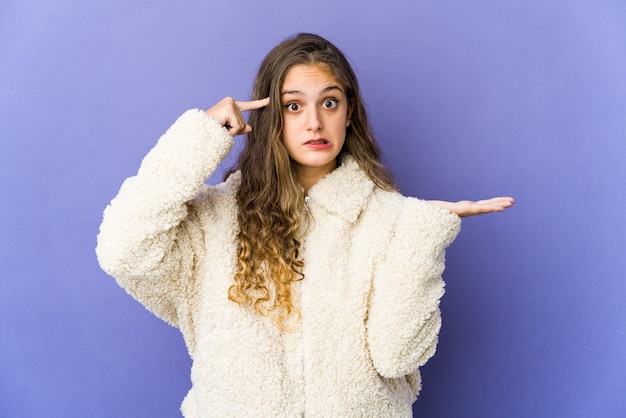 Jonge Kaukasische leuke vrouw die een product bij de hand houdt en toont.