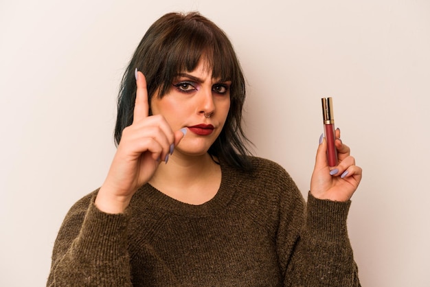 Jonge Kaukasische make-up artiest vrouw met een lipgloss geïsoleerd op een witte achtergrond met een idee inspiratie concept