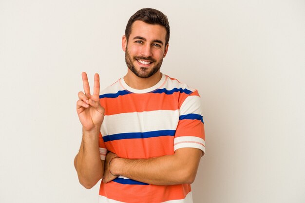 Jonge kaukasische mens die op witte muur wordt geïsoleerd die nummer twee met vingers toont