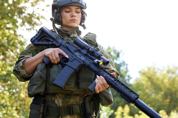 Jonge Kaukasische militaire vrouw controleert geweer in het bos alvorens te schieten