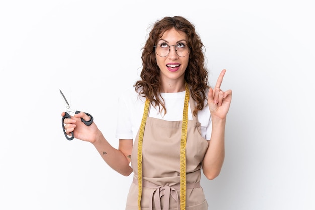 Jonge kaukasische naaistervrouw die op witte achtergrond wordt geïsoleerd en een idee denkt dat de vinger omhoog wijst