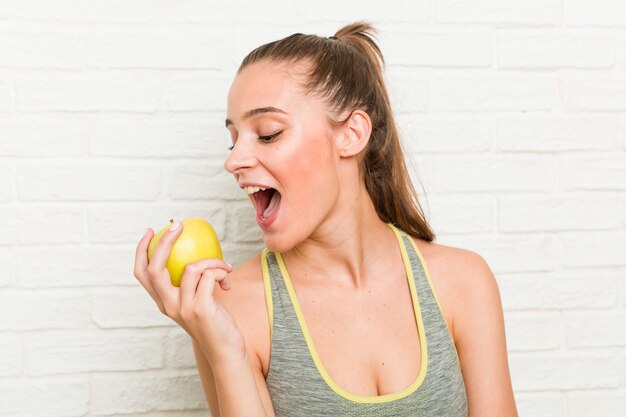 Jonge Kaukasische sportieve vrouw die een appel houdt