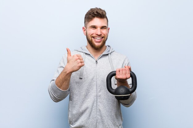 Jonge Kaukasische sportman die een halter houdt die en duim opheft