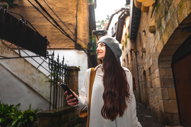 Jonge kaukasische toeristenvrouw die de smartphone in een oude stad gebruikt.
