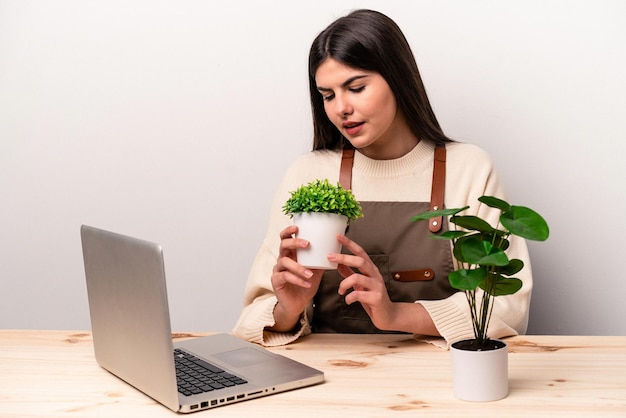 Jonge kaukasische tuinmanvrouw die aan de lijst werkt die op witte achtergrond wordt geïsoleerd