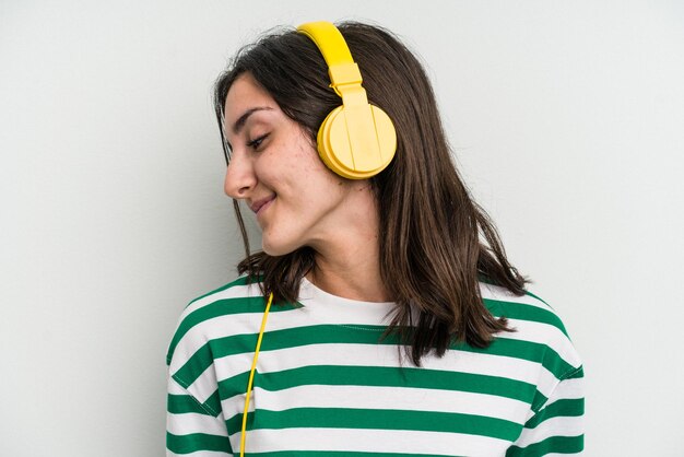 Jonge kaukasische vrouw die aan muziek luistert die op witte achtergrond wordt geïsoleerd