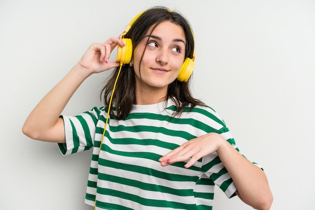 Jonge kaukasische vrouw die aan muziek luistert die op witte achtergrond wordt geïsoleerd