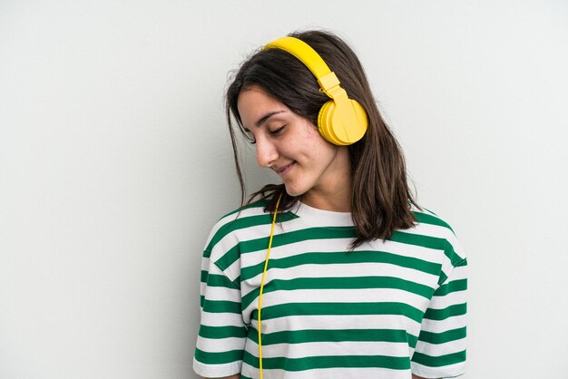Jonge kaukasische vrouw die aan muziek luistert die op witte achtergrond wordt geïsoleerd