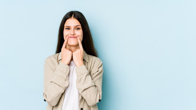 Jonge Kaukasische vrouw die bij het blauwe muur twijfelen tussen twee opties wordt geïsoleerd.