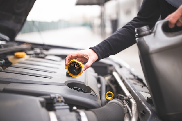 Jonge Kaukasische vrouw die de motorolie van de auto controleert. Auto onderhoud concept.