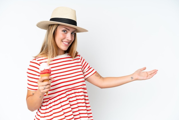 Jonge kaukasische vrouw die een cornetroomijs houdt dat op witte achtergrond wordt geïsoleerd die handen aan de kant uitbreidt om uit te nodigen om te komen