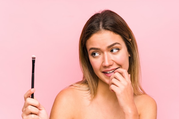 Jonge Kaukasische vrouw die een eyebrush ontspannen het denken over iets houdt